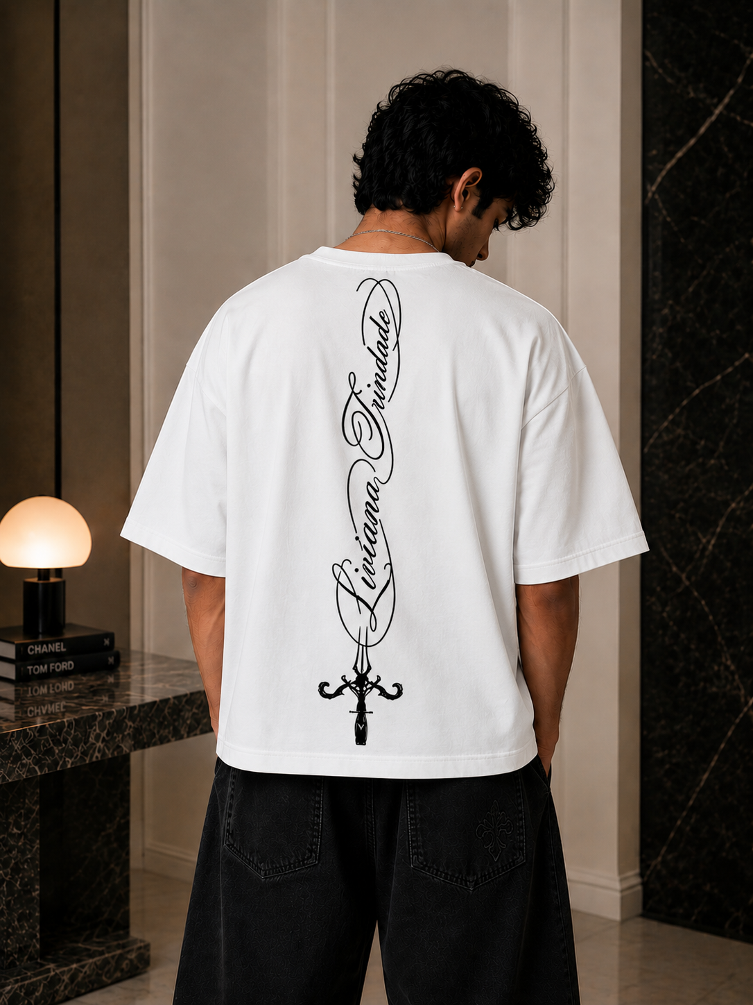 Person wearing a white t-shirt with black text and design on the back, standing in an indoor setting.