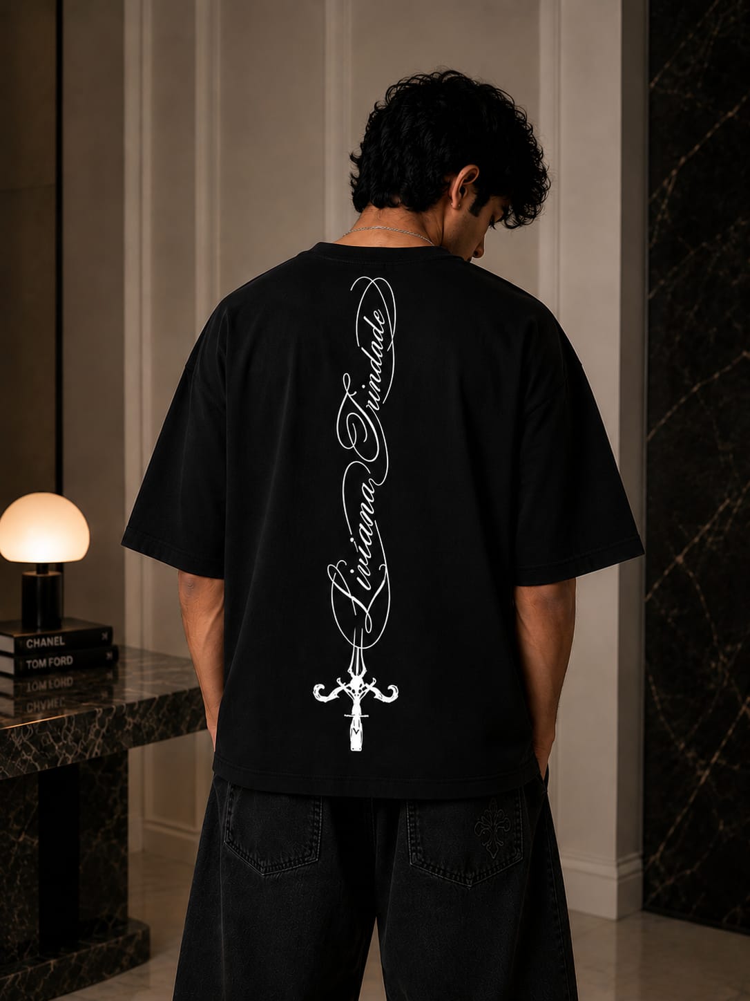Person wearing a black t-shirt with white graphics and text indoors.