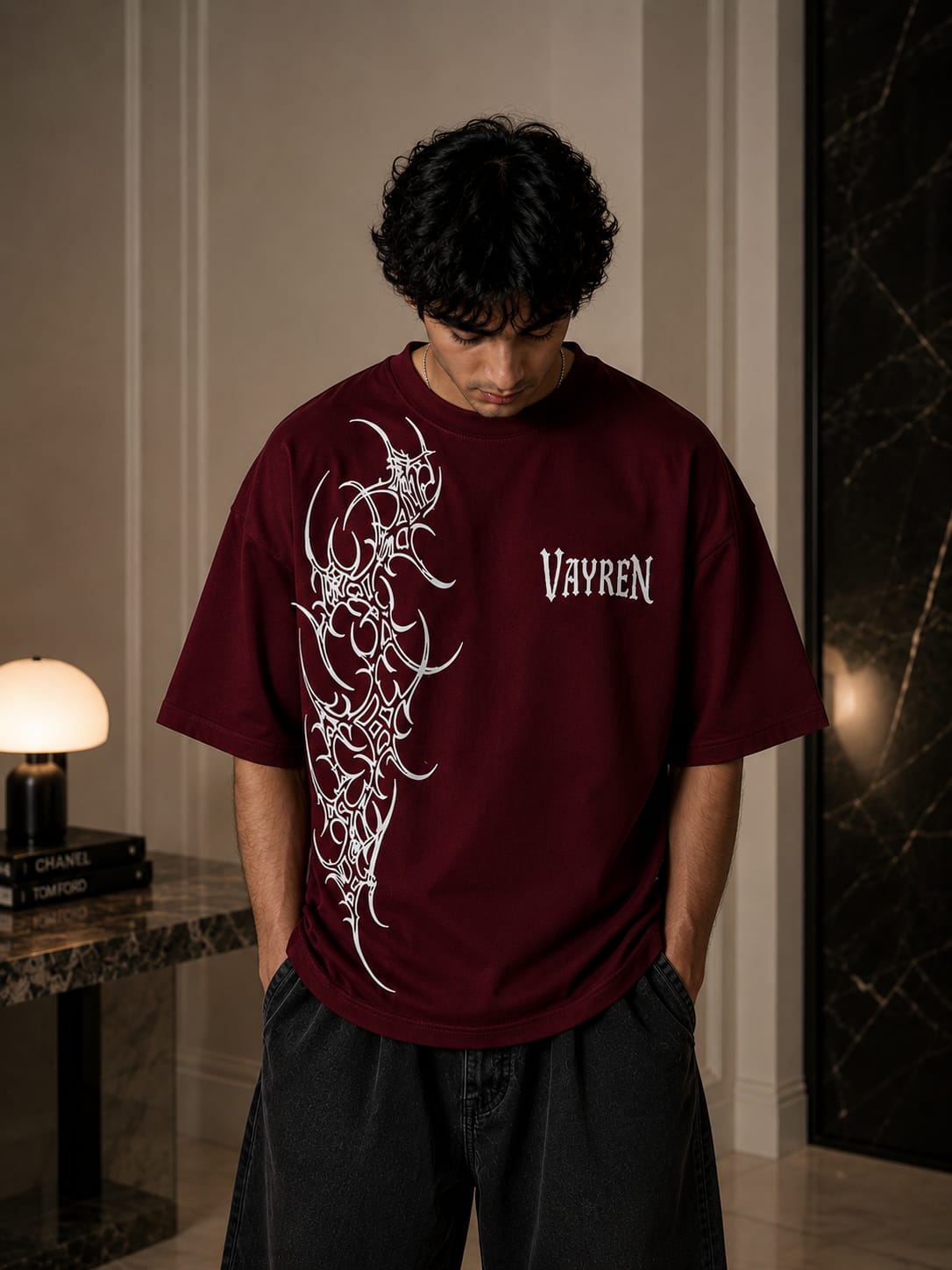 Person wearing a maroon t-shirt with white graphics and text indoors.