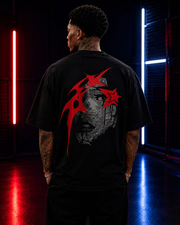 Person wearing a black t-shirt with a graphic design on the back in a dark room with neon lights.